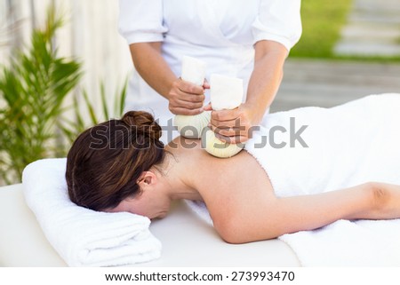 Brunette having massage with herbal compresses in the health spa