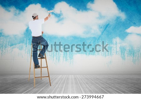 Man on ladder painting with roller against painted sky