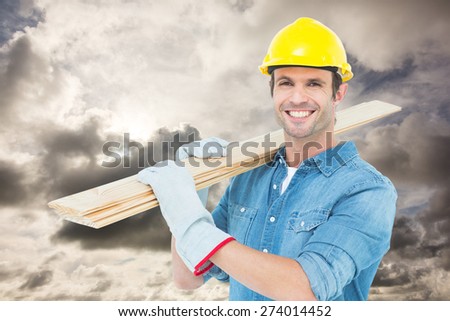 Happy carpenter carrying wooden planks against blue sky with white clouds
