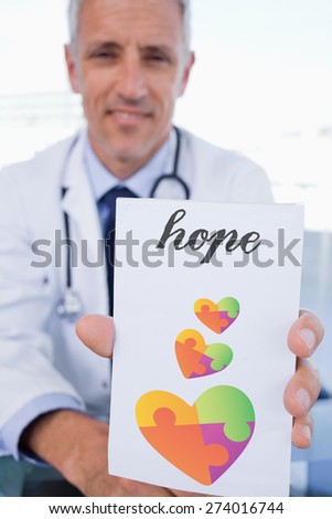 The word hope and portrait of a male doctor showing a blank prescription sheet against autism awareness heart