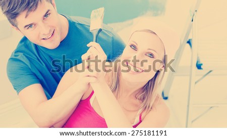 Hugging couple having fun while painting a room in their new house