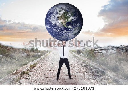 Businessman carrying the world against stony path leading to misty city horizon