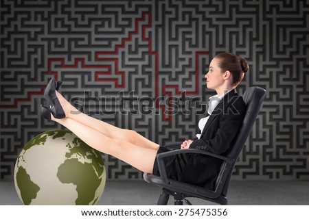 Businesswoman sitting on swivel chair with feet up against grey maze
