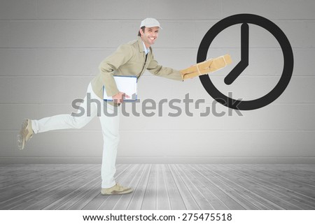 Happy delivery man running while holding parcel against grey room