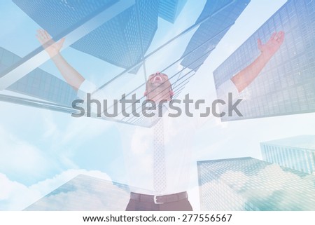 Handsome businessman cheering with arms up against skyscraper