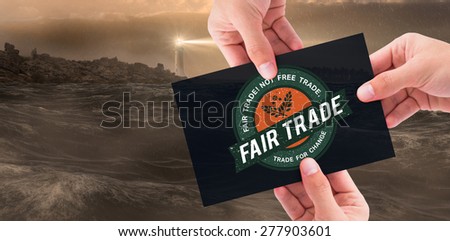 Hand showing card against stormy sea with lighthouse