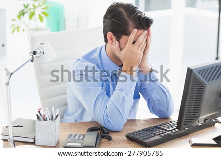 Upset businessman hiding his face in the office