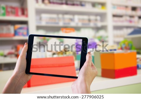 Finger pointing to tablet against close up of shelves of drugs