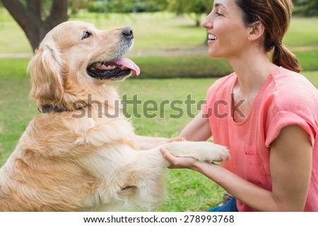 Pretty brunette playing with her dog in the park on a sunny day