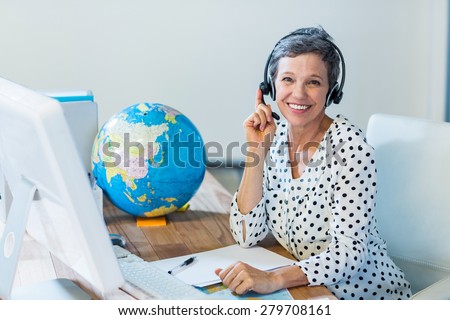 Smiling travel agent sitting at her desk in the office