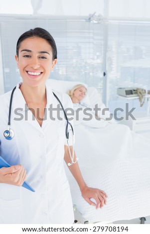 Smiling doctor looking at camera in patients room in hospital