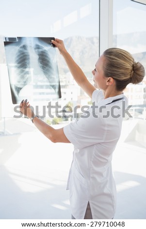 Doctor looking at Xray beside windows in hospital