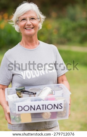 Happy grandmother holding donation box on a sunny day