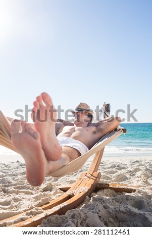 Handsome man resting in the hammock at the beach