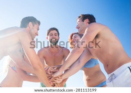 Group of friends standing in circle hands together at the beach