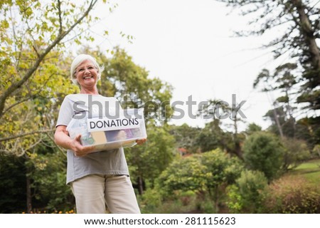 Happy grandmother holding donation box on a sunny day