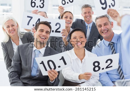 Smiling interview panel holding score cards in bright office