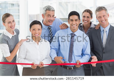 Business man cutting red strip in office
