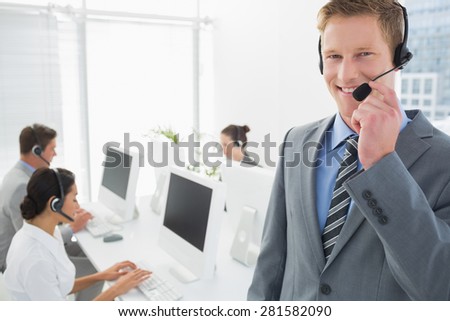 Smiling manager standing with staff behind in call center