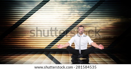 Businessman meditating in lotus pose against room with large window looking on landscape
