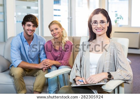 Psychologist and happy couple smiling at camera in the office