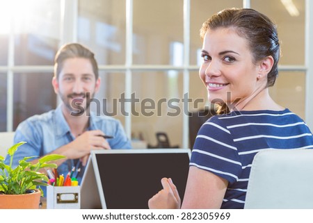 Smiling colleagues working together on laptop in the office