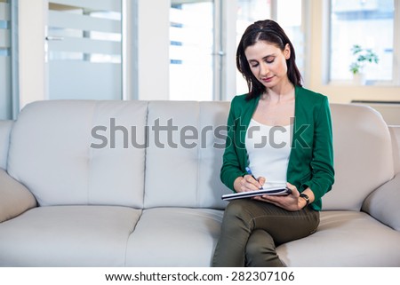 Psychologist sitting on the couch and taking notes in the office