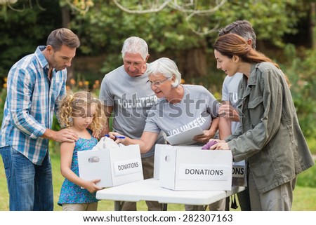 Happy volunteer family separating donations stuffs on a sunny day