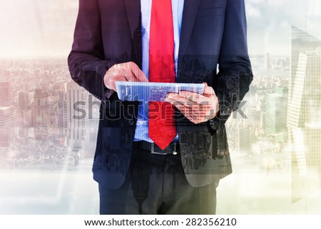 Businessman scrolling on his digital tablet against room with large window looking on city