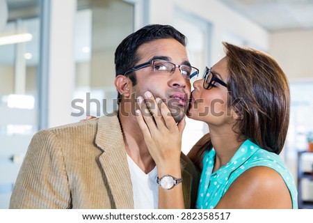 Beautiful brunette kissing her boyfriend in the office