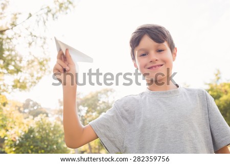Smiling boy with paper plane in the park on a sunny day