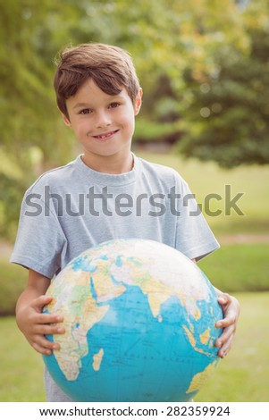 Smiling boy holding an earth globe in the park on a sunny day