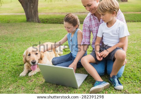 Happy family with their dog using laptop on a sunny day