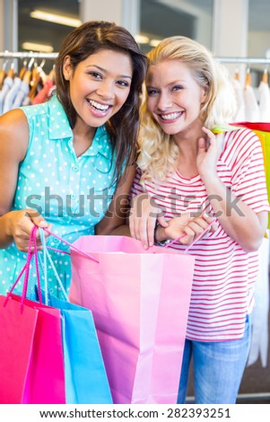Smiling friends holding shopping bags in clothes store