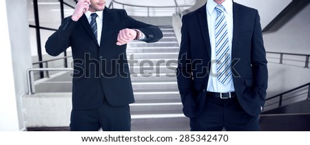 Smiling elegant businessman with hands in pockets against empty stair way