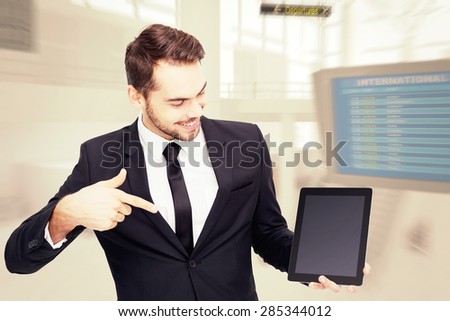 Happy businessman pointing with his tablet against airport terminal