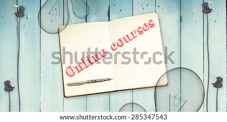 The word online courses against notepad and bulbs on wooden background