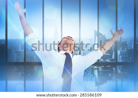 Handsome businessman cheering with arms up against room with large window looking on city