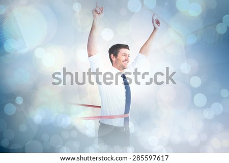 Businessman crossing the finish line against white glowing dots on grey