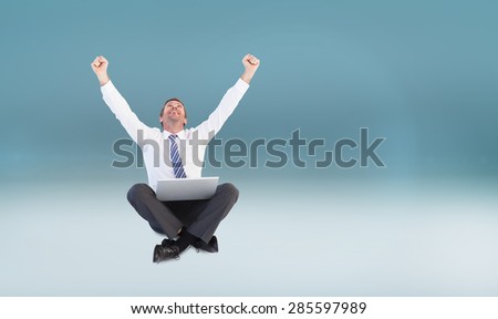Excited cheering businessman sitting using his laptop against blue vignette background