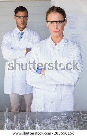 Serious scientists looking at camera arms crossed in laboratory