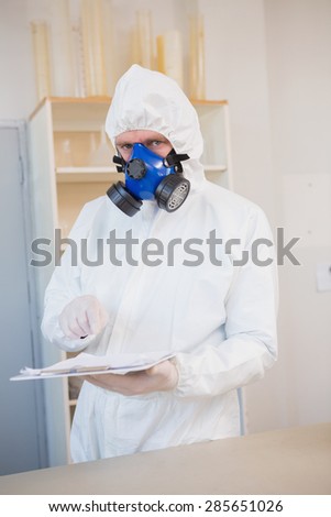 Scientist in protective suit pointing clipboard in the laboratory