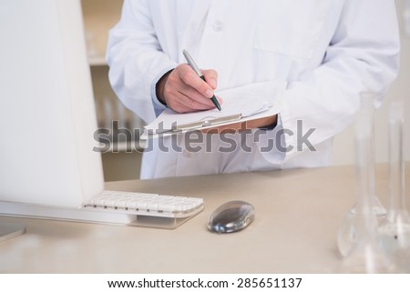 Scientist writing on clipboard in the laboratory