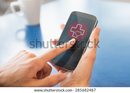 heart and cross against young student using his smartphone in cafe