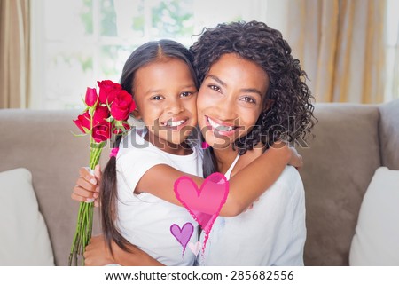 Valentines love hearts against pretty mother sitting on the couch with her daughter holding roses