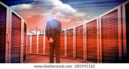 Rear view of mature businessman posing against composite image of server towers
