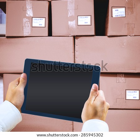 Man using tablet pc against cardboard boxes in warehouse