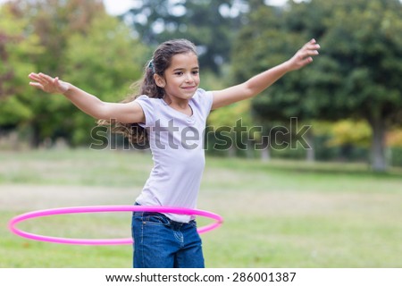 happy girl playing with hula hoops on a sunny day