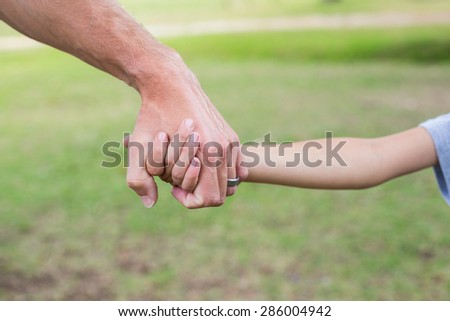 Father and son holding hands in the park on a sunny day