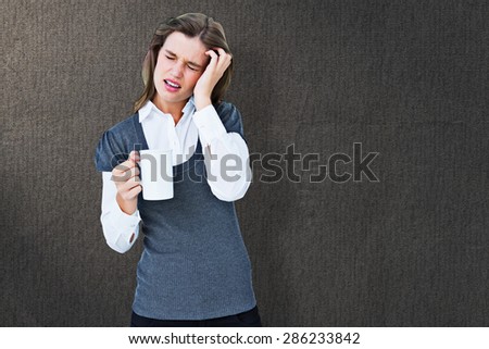Woman with headache holding mug against grey background